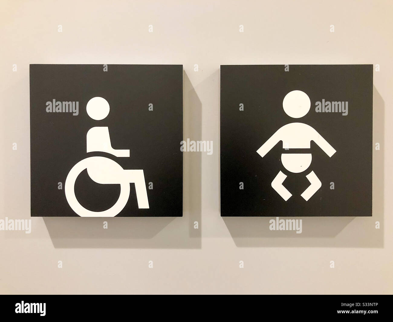 Invalidi e segnaletica per il cambio del bambino su una porta pubblica del gabinetto. - Immagine stock catturata con smartphone