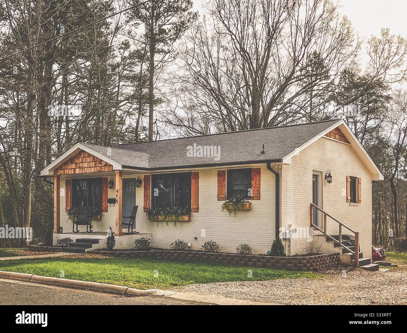 Affascinante cottage in mattoni dipinti di crema con persiane in legno Foto Stock