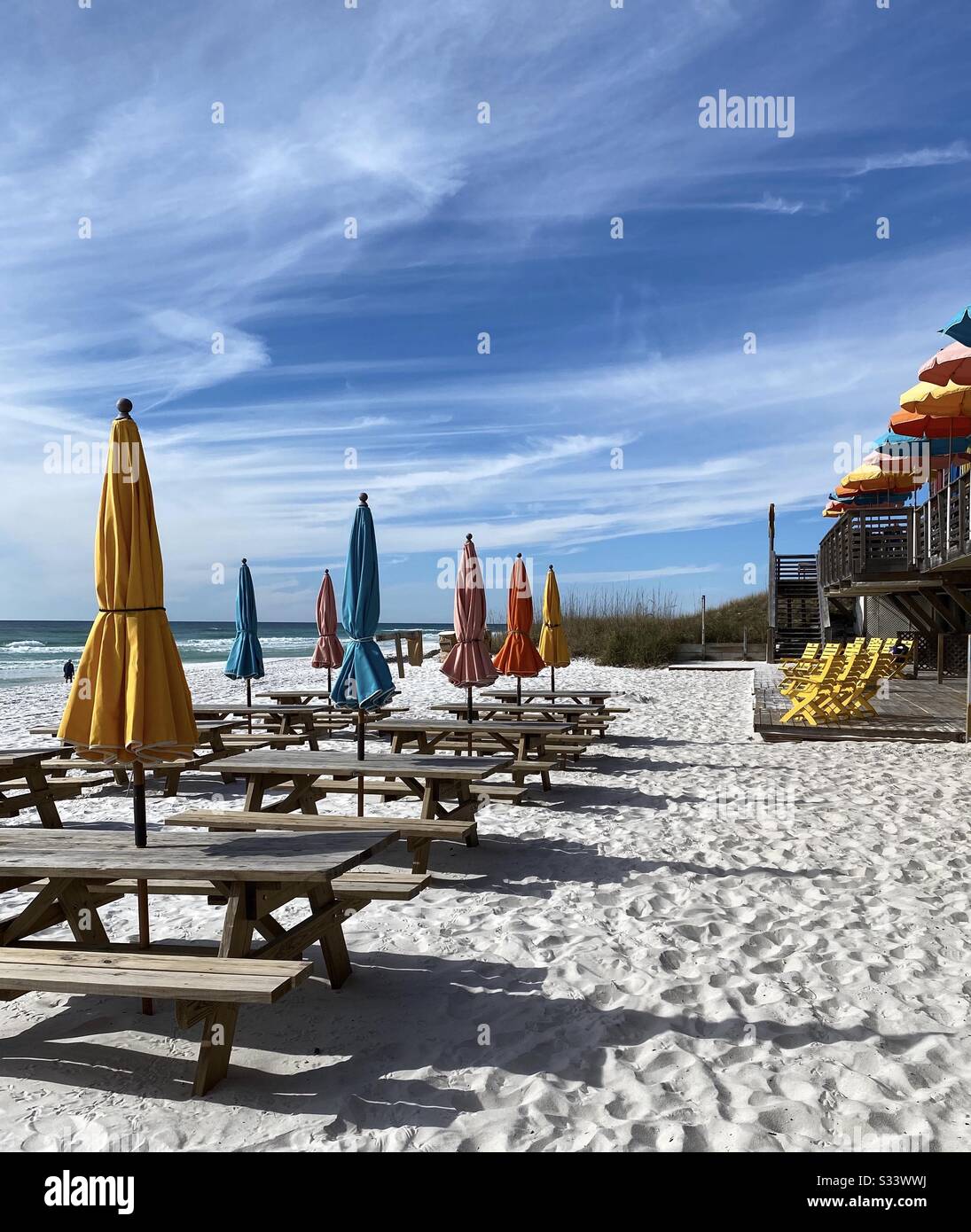 Tavoli da picnic all'aperto sulla spiaggia di sabbia bianca con sedie colorate e ombrelloni Foto Stock