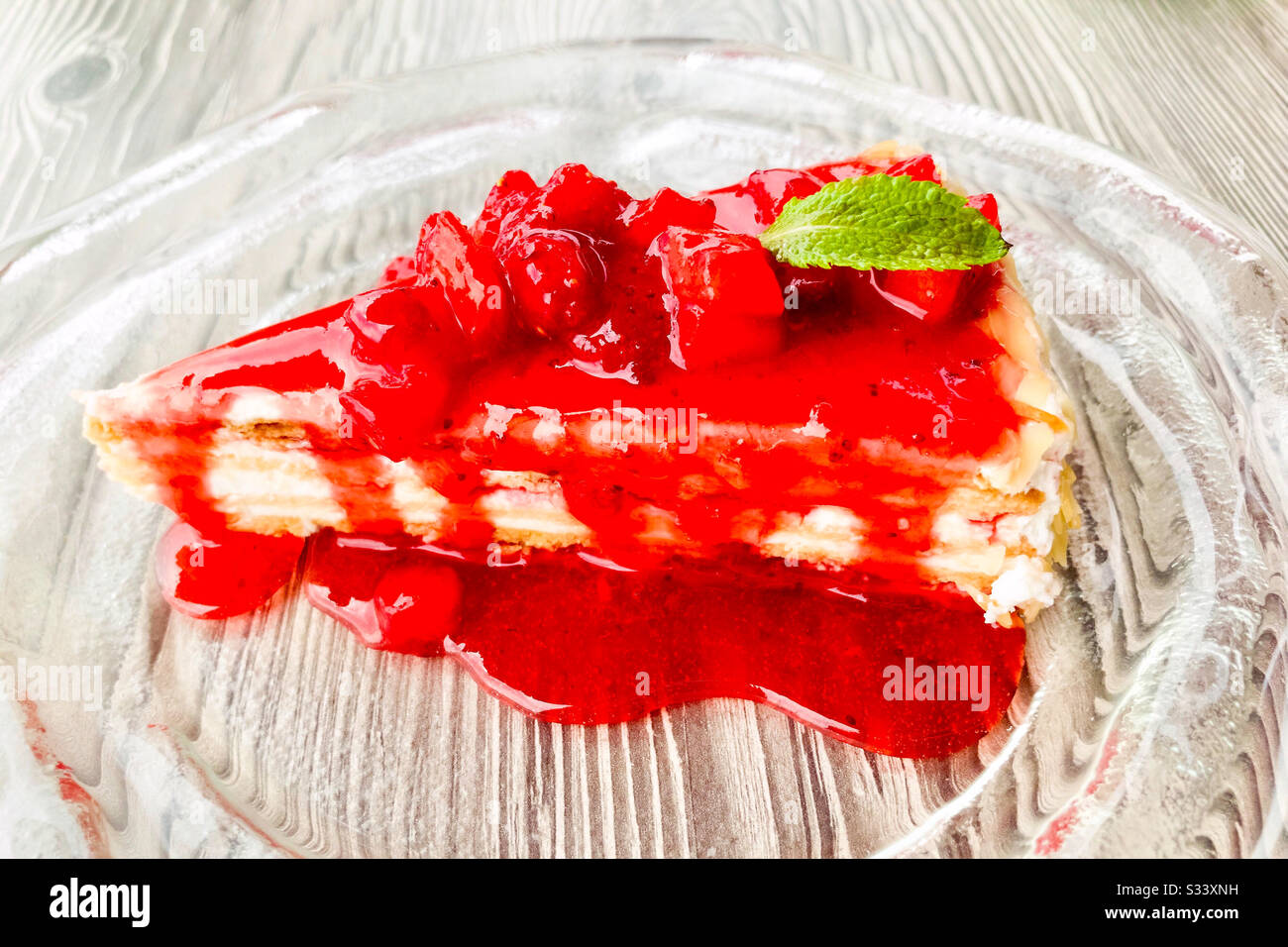 Una pace di torta di fragole su una lastra di vetro decorata con una foglia di menta. - Immagine stock catturata con smartphone