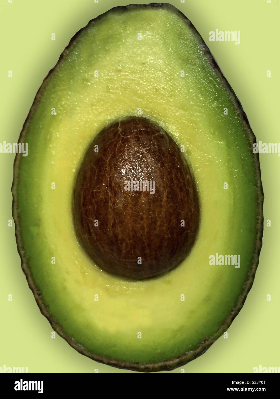 Dieta a base di piante. Avacado mezzo su sfondo giallo verde Foto Stock