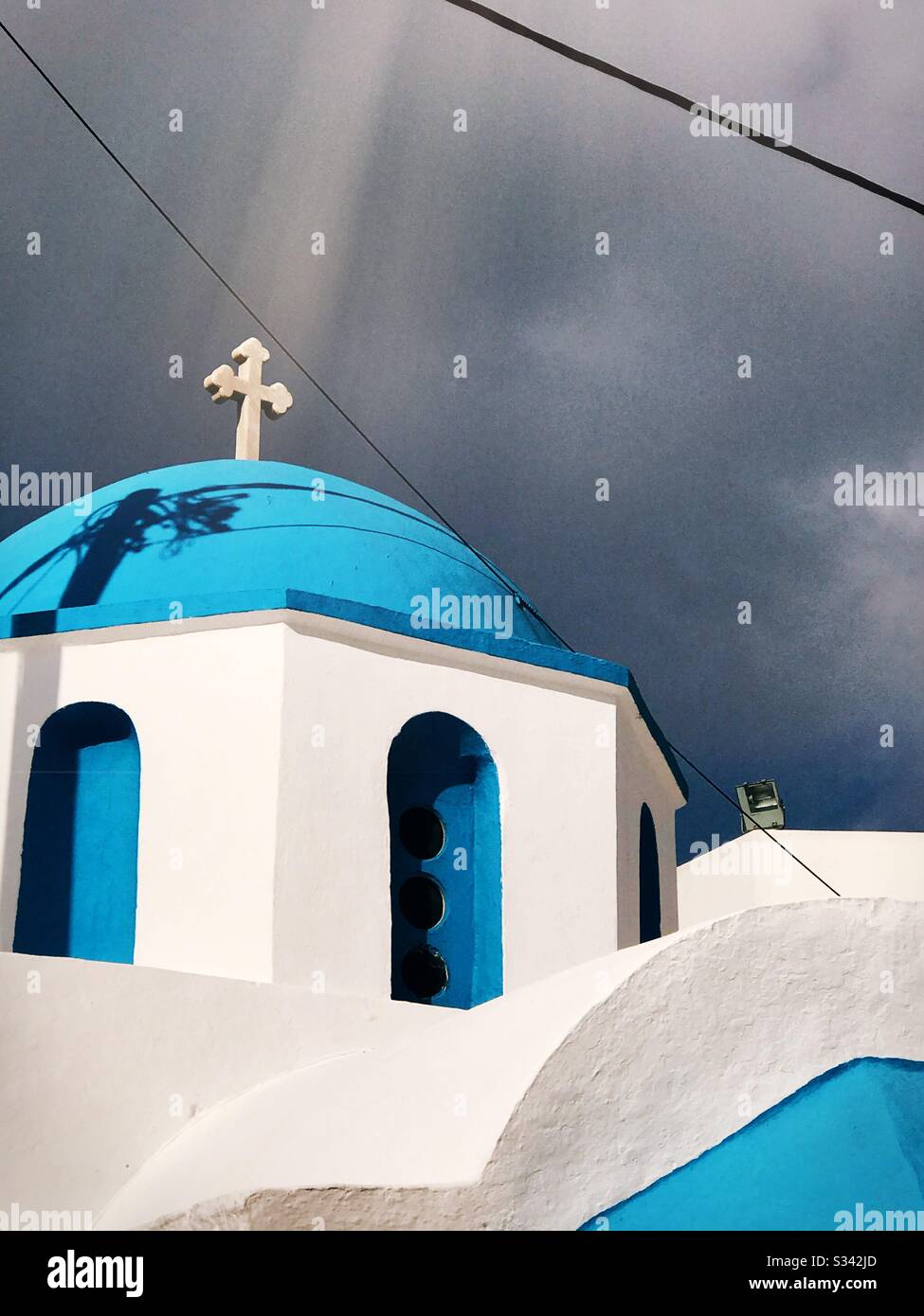 Un raggio di sole splende in una croce su un tetto blu di una chiesa ortodossa greca sull'isola greca di Naxos Foto Stock