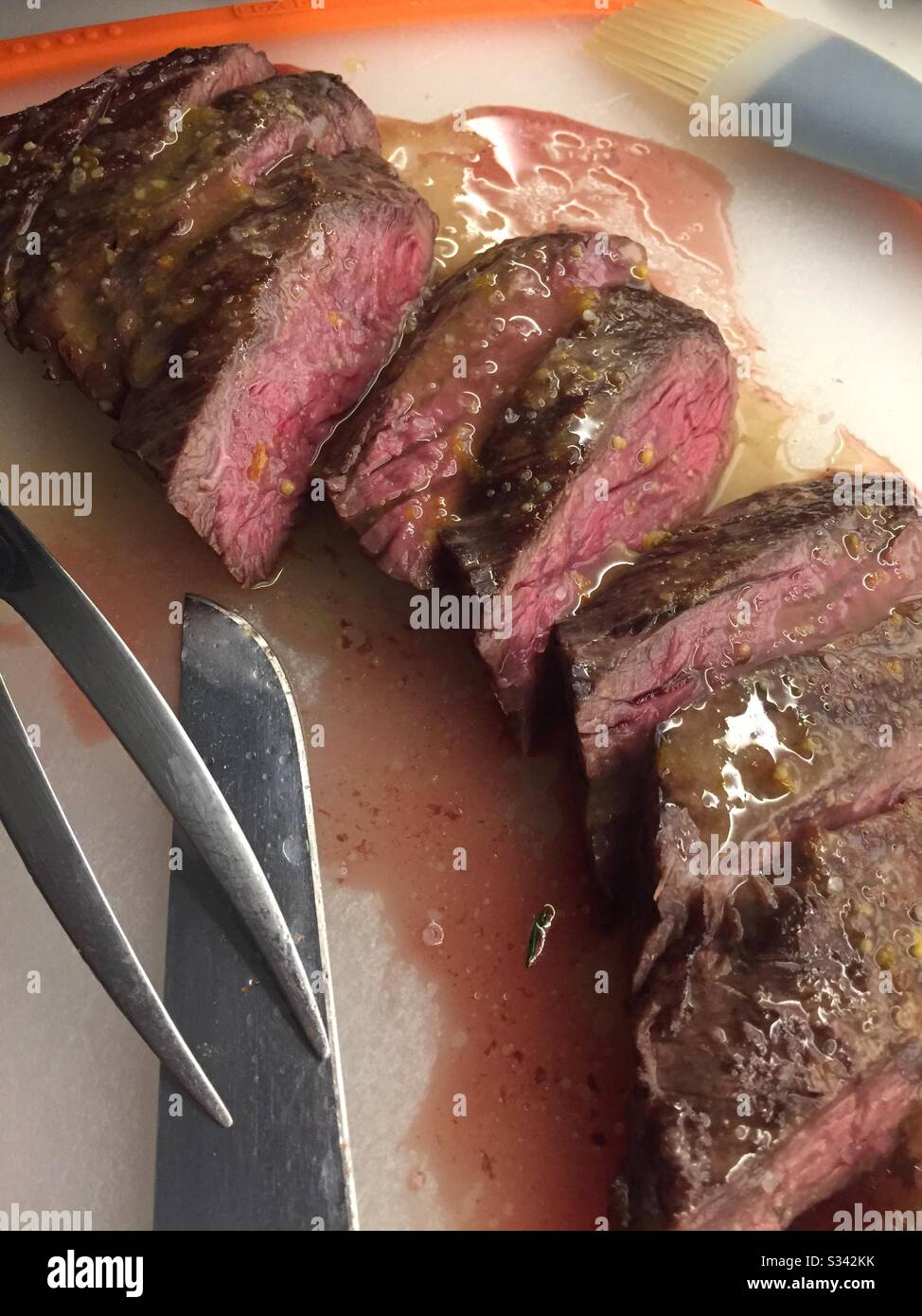 Una bistecca di gonna media rara scolpita su un tagliere in una cucina residenziale. Foto Stock
