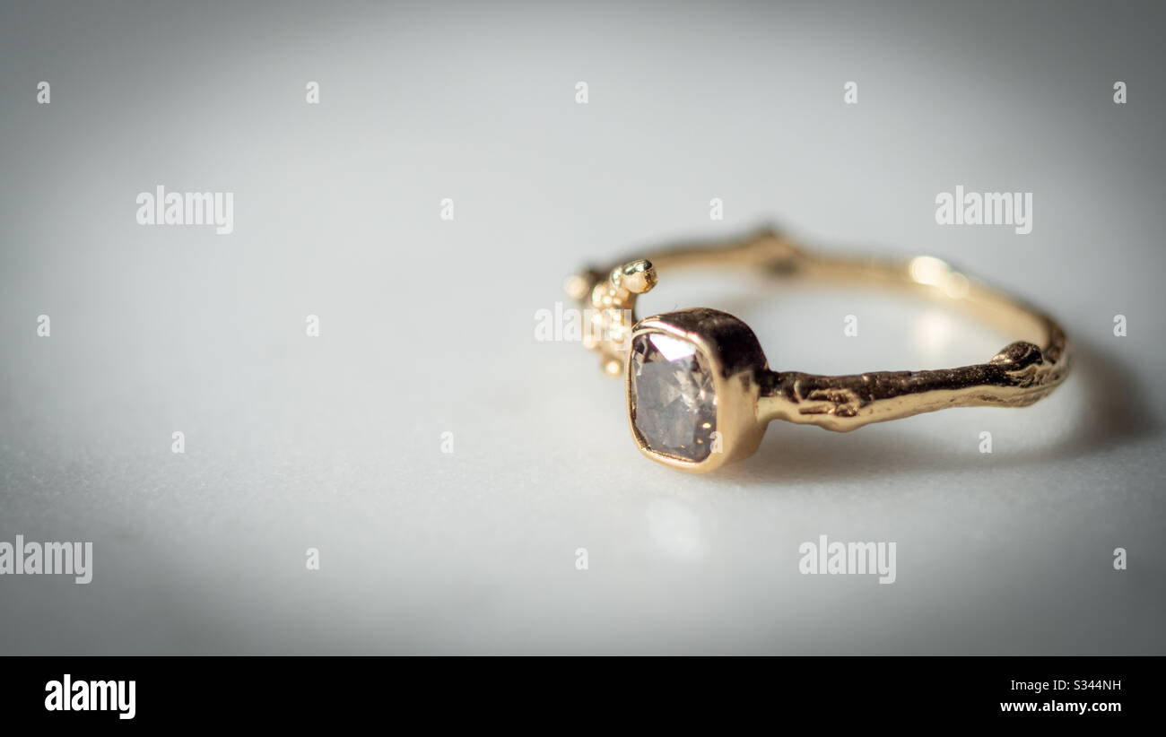 Anello d'oro con un diamante su un tavolo in marmo Foto Stock