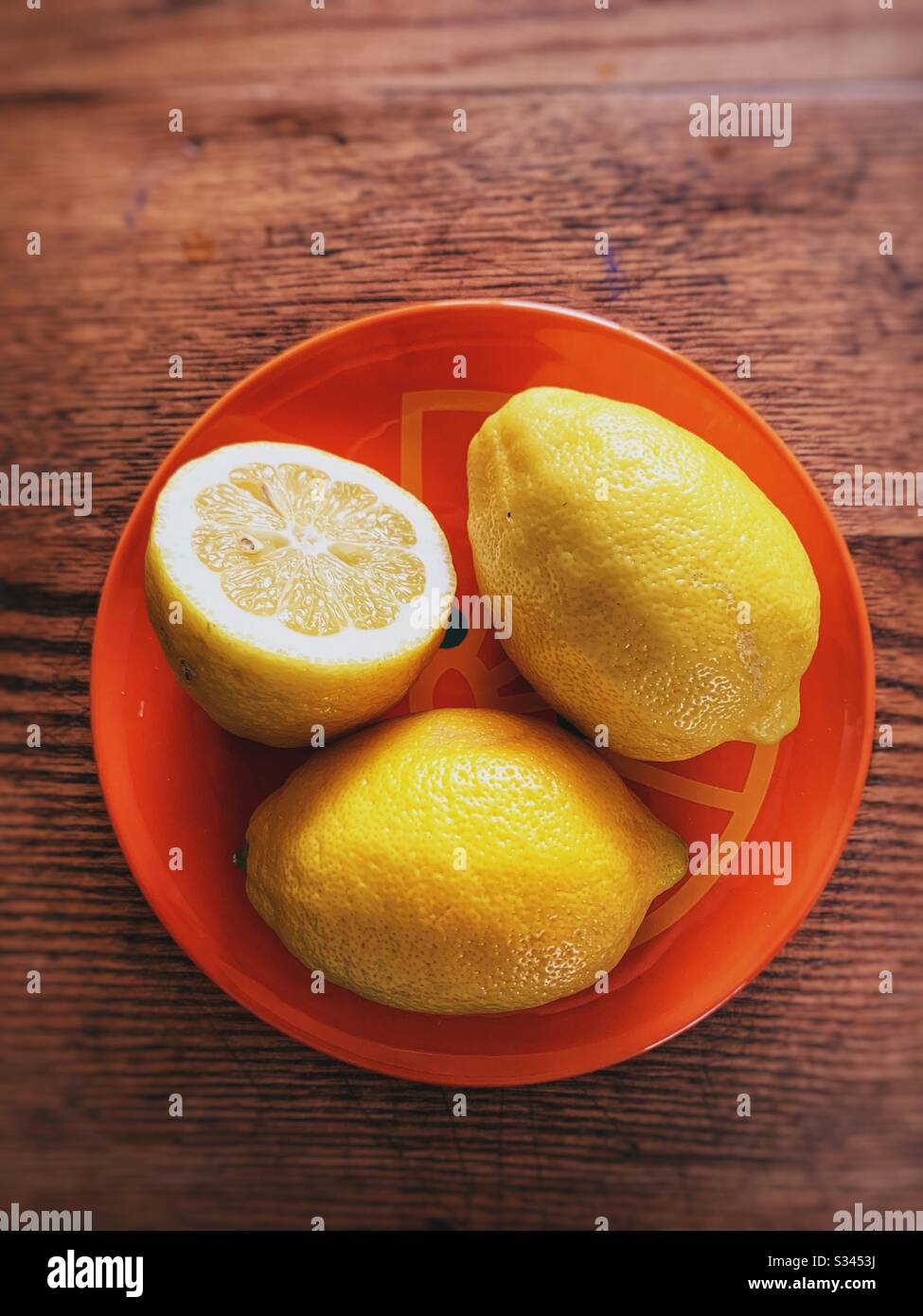Tagliare il limone fresco su un piatto d'arancia Foto Stock