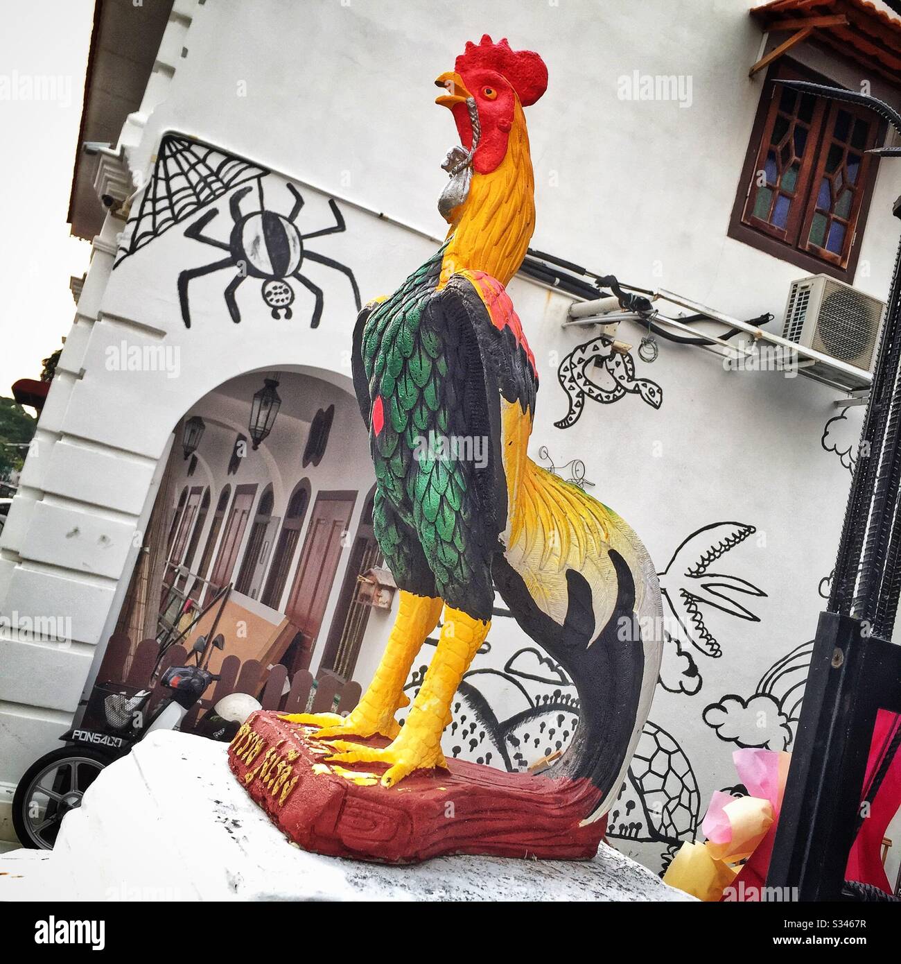 Statuette dipinta di un gallo fuori di un ristorante a George Town, Penang, Malesia Foto Stock