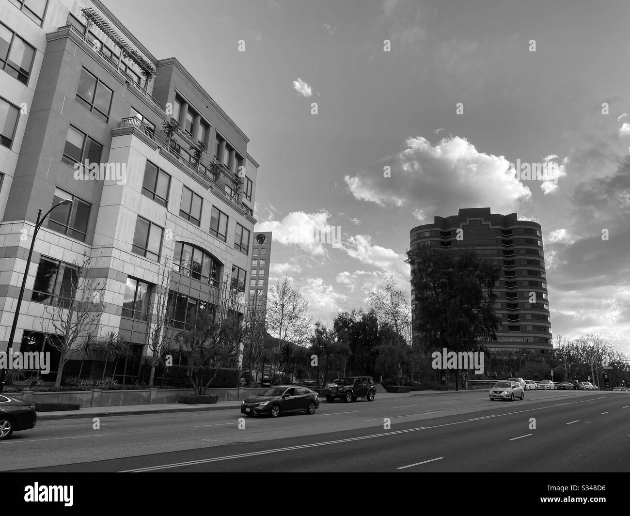 BURBANK, CA, FEBBRAIO 2020: Edifici di uffici moderni con traffico in primo piano e cielo nuvoloso, bianco e nero Foto Stock