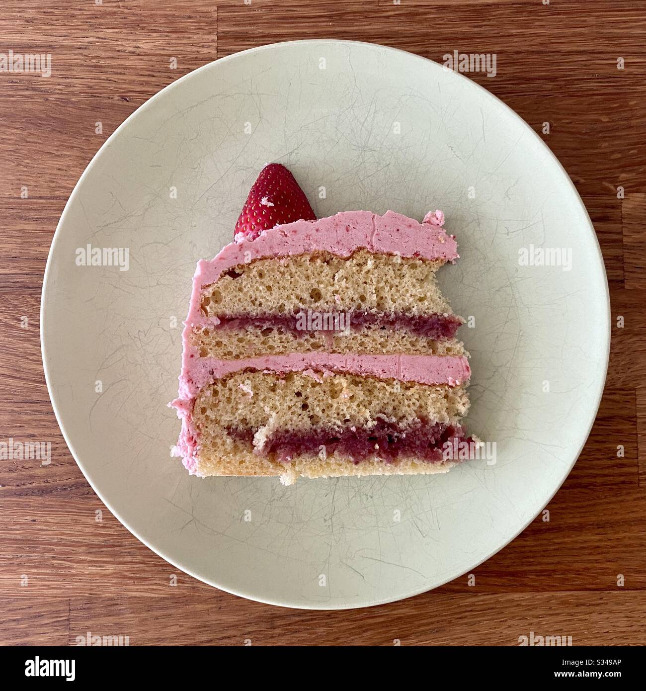 Fetta di torta di fragole, con glassa di fragole rosa, strati di confettura di fragole ripieno e spugna alla vaniglia, su piatto bianco Foto Stock