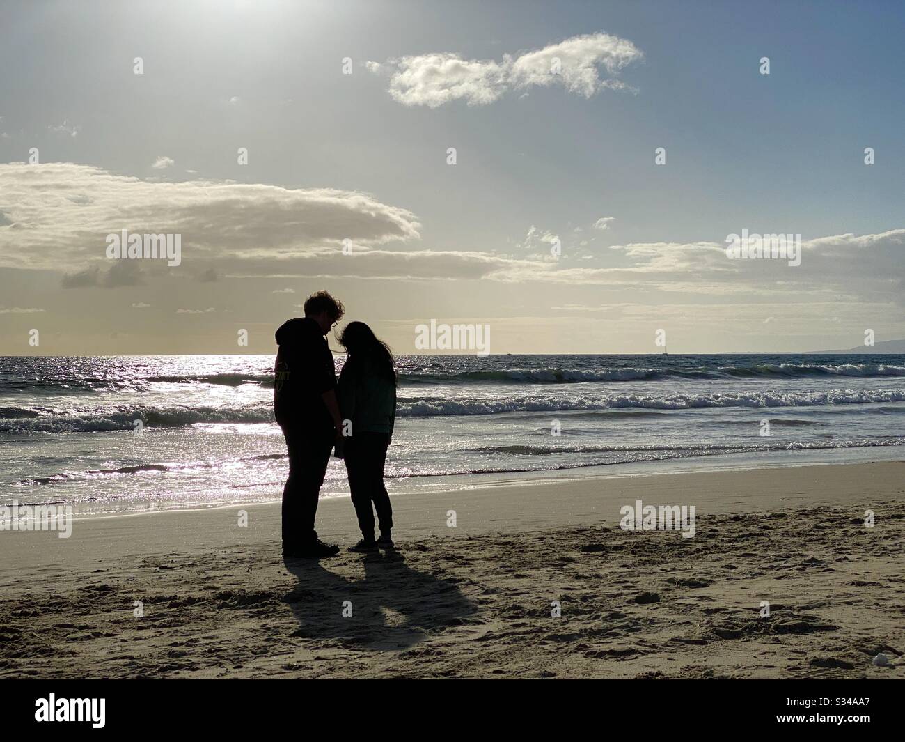 SANTA MONICA, CA, MAR 2020: Giovane coppia silhouetted contemplare la vita mentre in piedi sulla spiaggia, accanto all'Oceano Pacifico, nel tardo pomeriggio Foto Stock