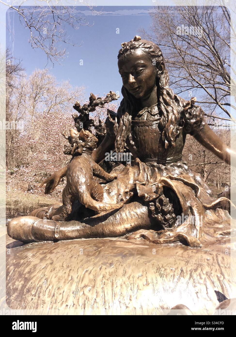 La scultura di Alice in Wonderland nel parco centrale è circondata da ciliegi in fiore in primavera, NYC, Stati Uniti Foto Stock