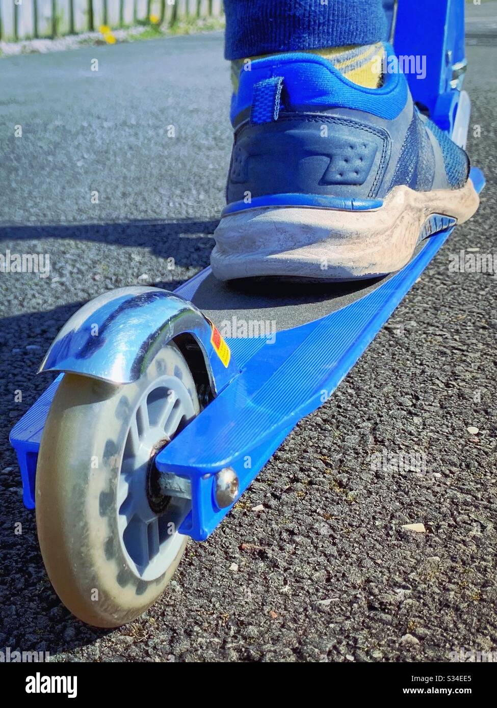 Piede del bambino su uno scooter blu. Rimanere attivi. Andando a parcheggiare. Esercizio durante la crisi del coronavirus Foto Stock