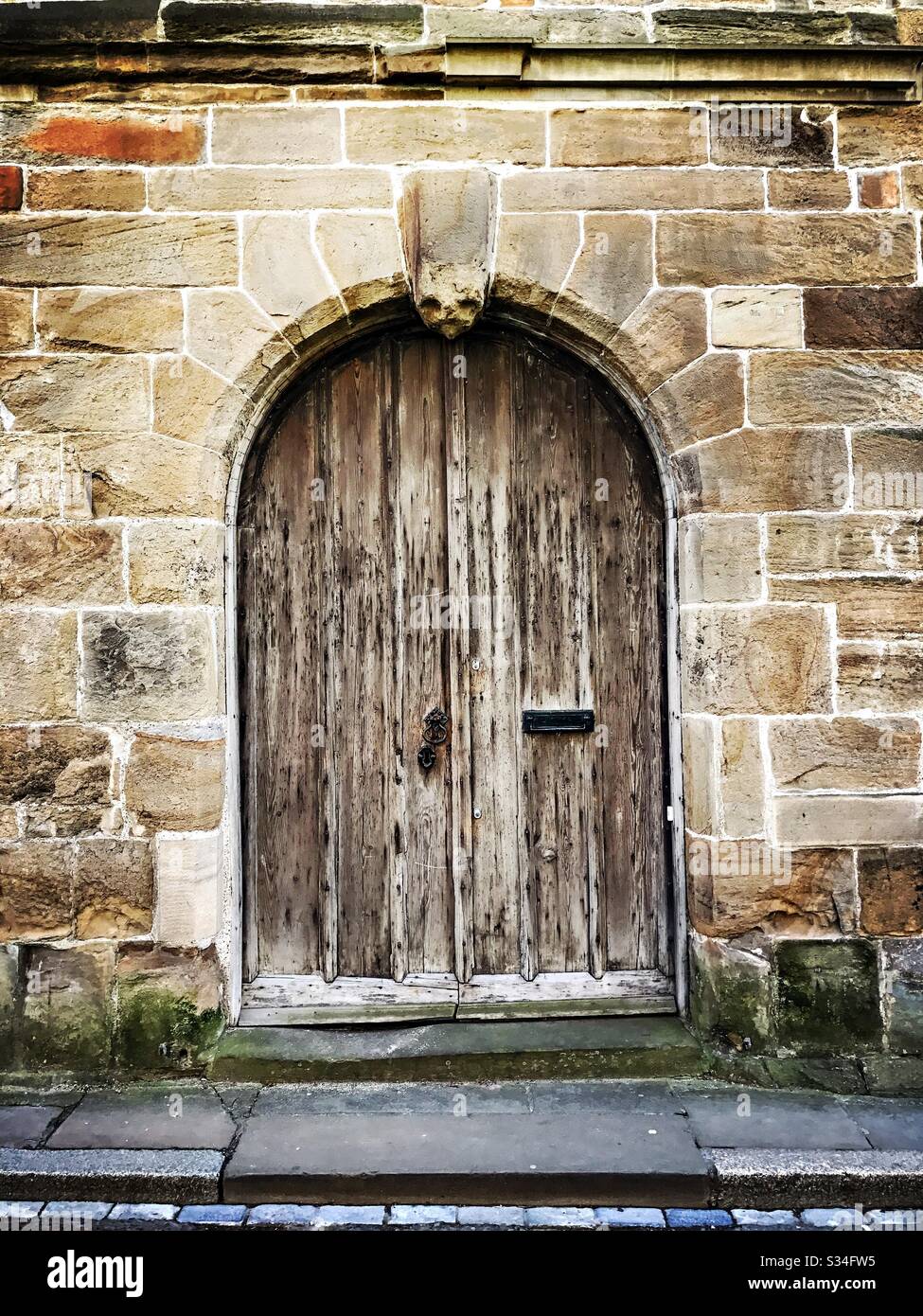 Architettura di Durham City, Inghilterra nord-orientale. Porta medievale in legno con arco e tradizionale muro di pietra - Immagine stock catturata con smartphone