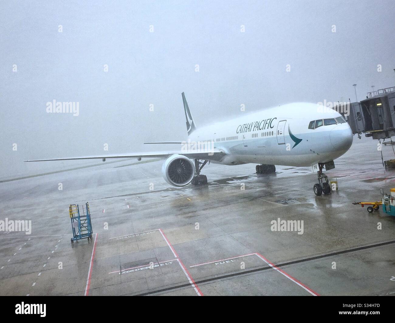 A Cathay Pacific Airways Boeing 777 sul grembiule in forte pioggia all'Aeroporto Internazionale di Hong Kong - Immagine stock catturata con smartphone