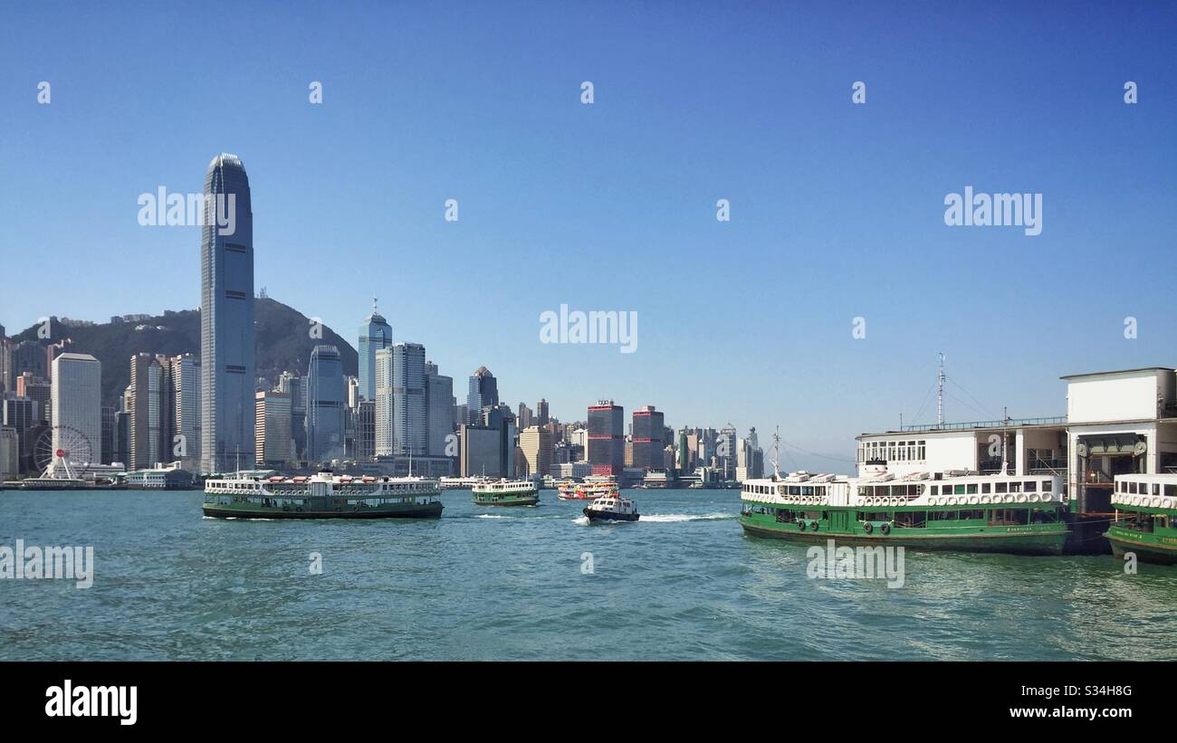Gli iconici Star Ferries trasportano passeggeri attraverso il Victoria Harbour tra Tsim Sha Tsui a Kowloon e l'Isola di Hong Kong - Immagine stock catturata con smartphone