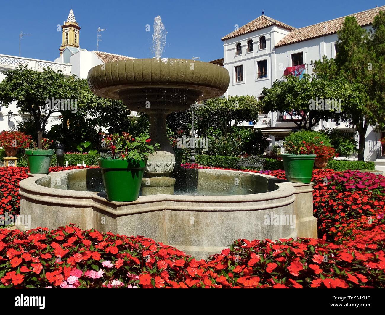 Splendidi fiori intorno a una fontana nel centro di Estepona nel sud della Spagna Foto Stock