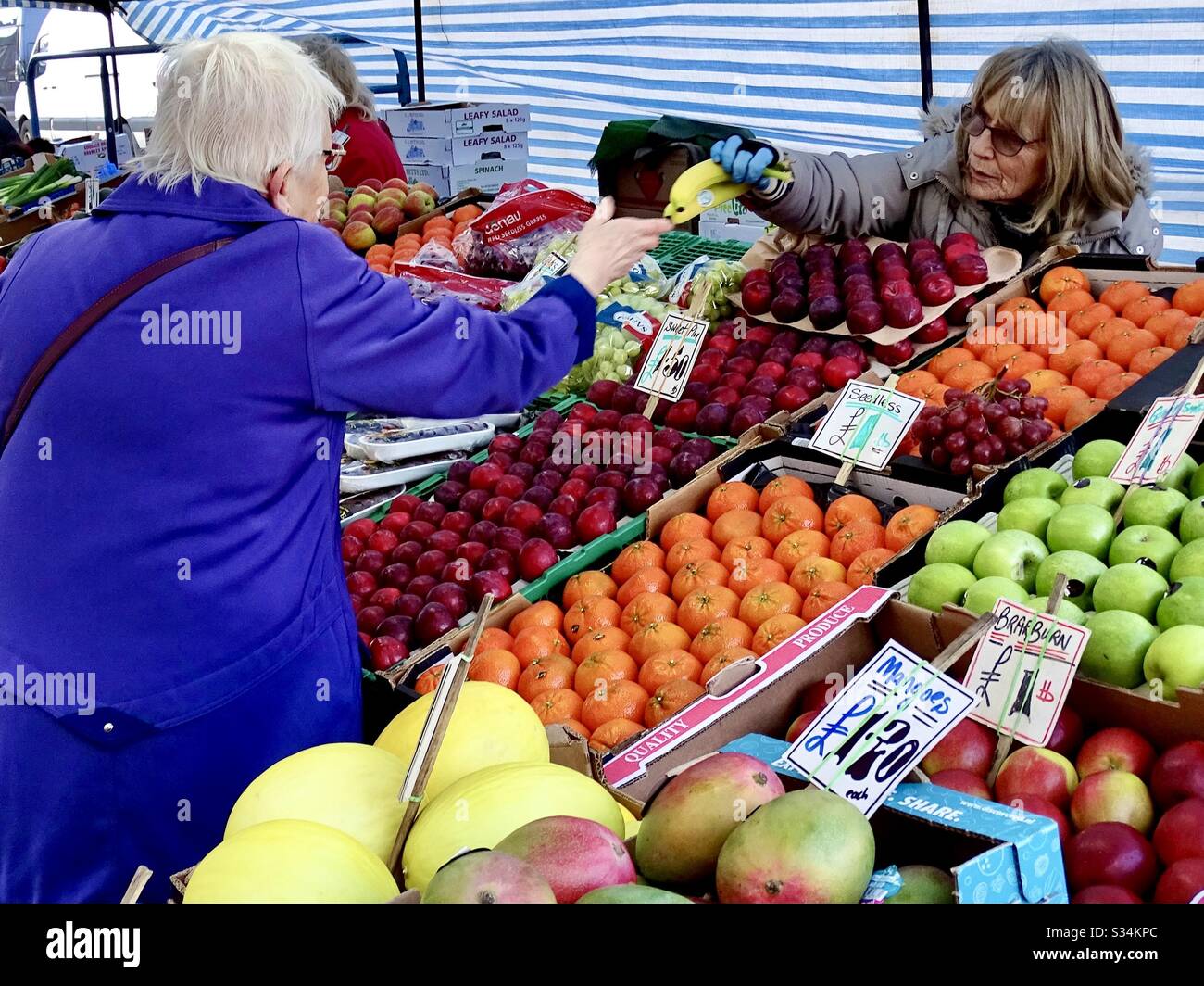Mercato stallholders a Leighton Buzzard, Inghilterra che vende frutta e verdura a un cliente Foto Stock