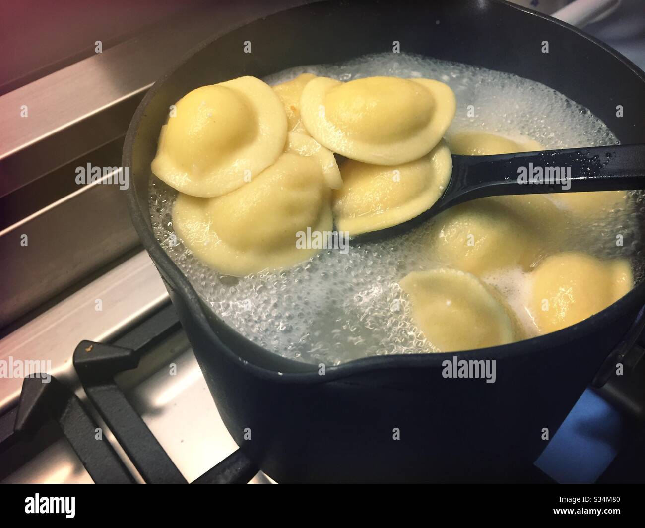 Ravioli freschi bollendo su un bruciatore residenziale di cima di stufa Foto Stock
