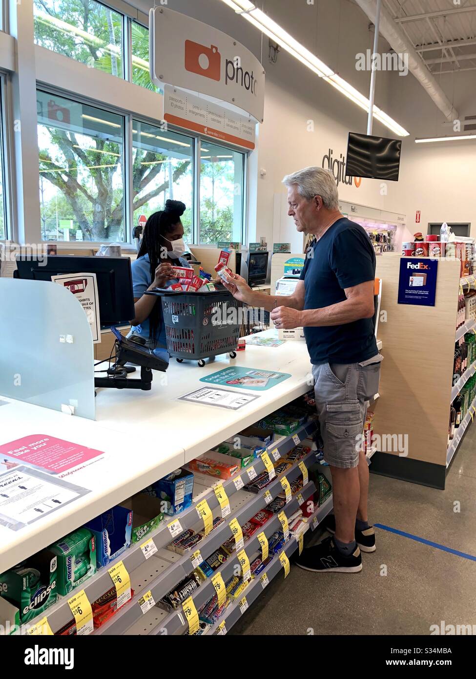 Il commesso che mostra un cliente Tylenol che è tenuto dietro il banco ad un deposito di Walgreens dovuto l'imbarco durante la pandemia di Covid-19, 31 marzo 2020. Foto Stock