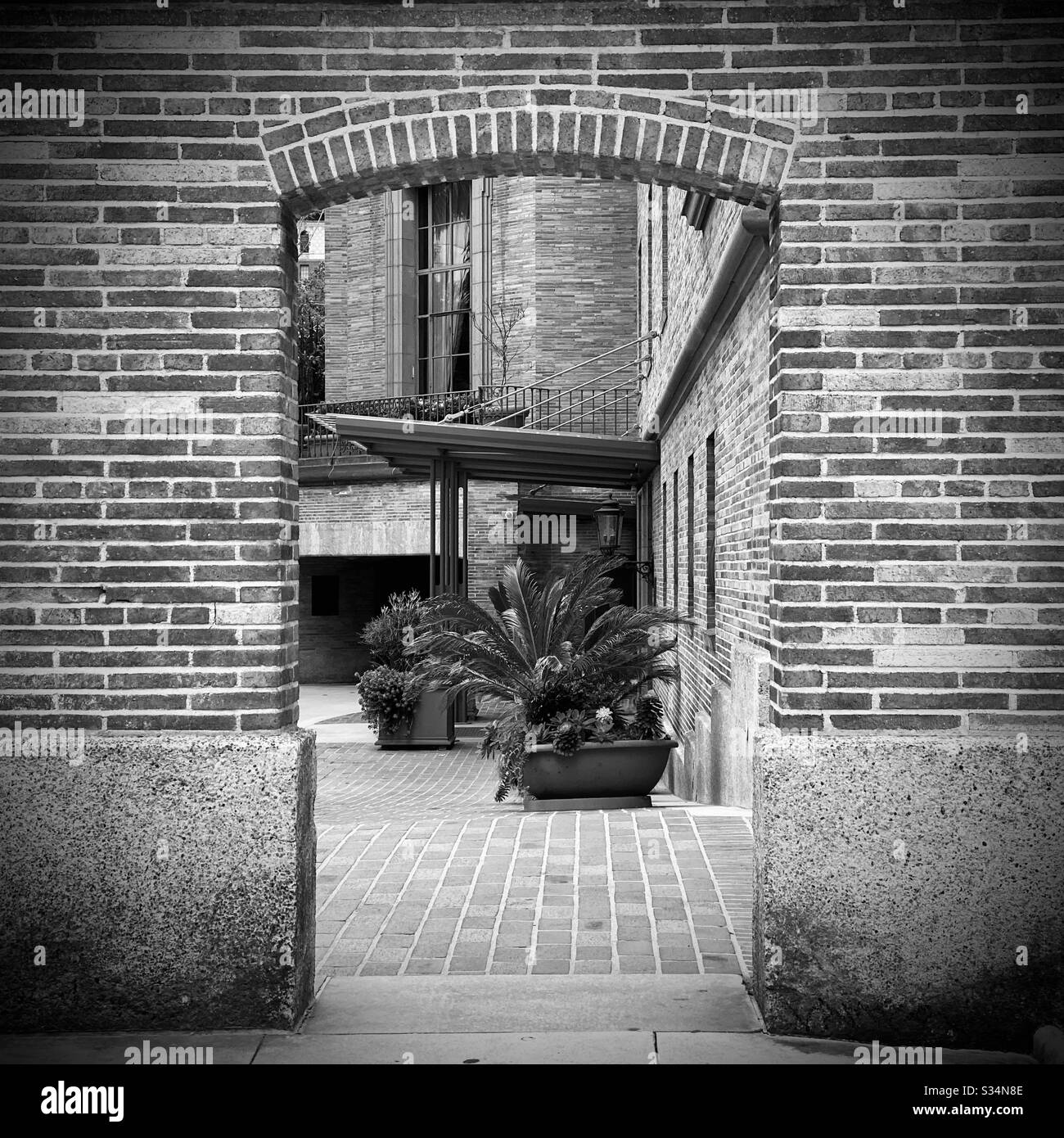 LOS ANGELES, CA, MAR 2020: Vista attraverso la porta in mattoni a muro per l'ingresso al California Club nel centro città. Bianco e nero. - Immagine stock catturata con smartphone