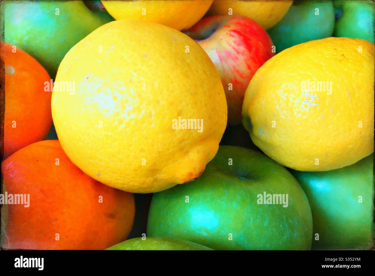 Pezzi di frutta colorati, tra cui mele, limoni e arance, in una ciotola di frutta Foto Stock