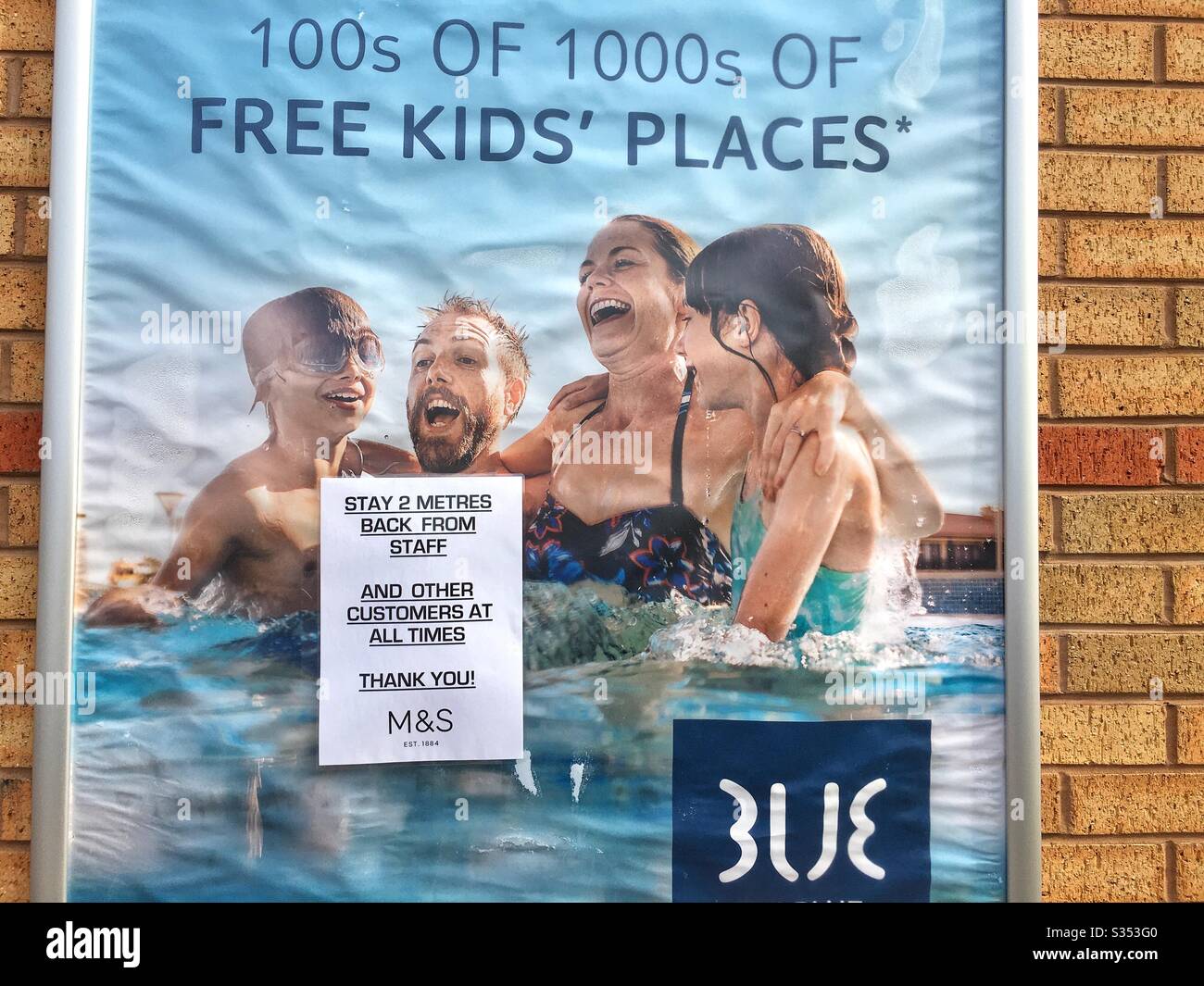 Posizionamento ironico di un cartello di distanza sociale su un poster di vacanza, Marks and Spencer, Northampton UK Foto Stock