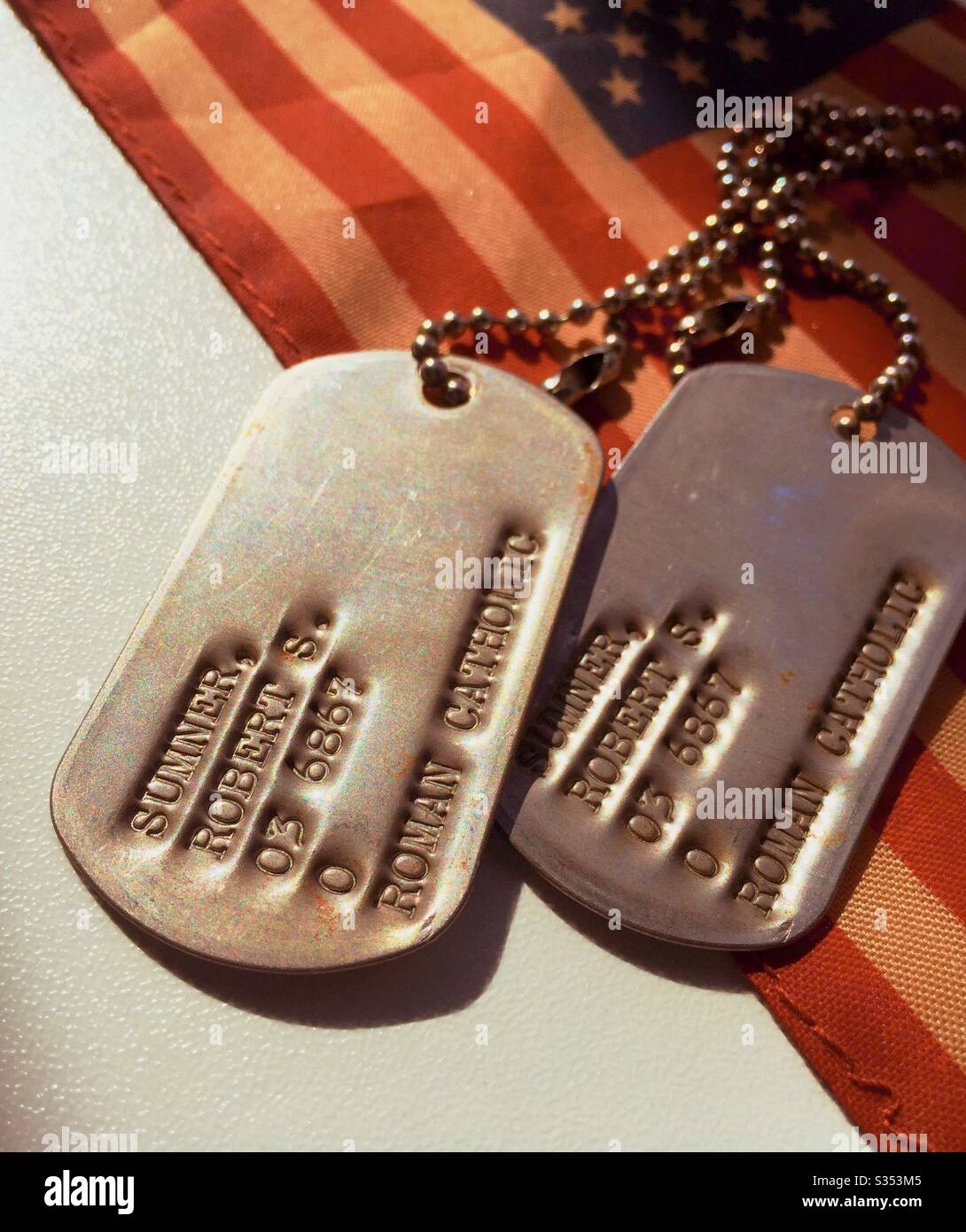 I tag dei cani dell'epoca dell'esercito STATUNITENSE della seconda guerra mondiale sono visualizzati su una bandiera americana, USA - Immagine stock catturata con smartphone