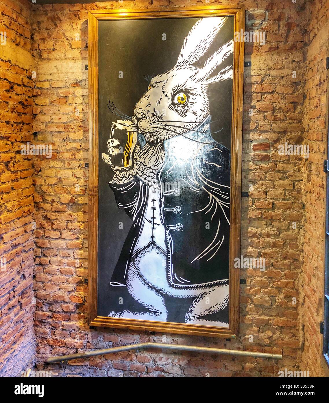 Un disegno di una birra bevuta di coniglio appeso su una parete di mattoni di un ristorante. - Immagine stock catturata con smartphone