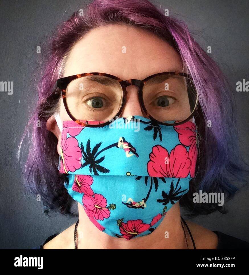 Donna che indossa una maschera facciale colorata e fiammeggiante durante la pandemia Covid-19 Foto Stock