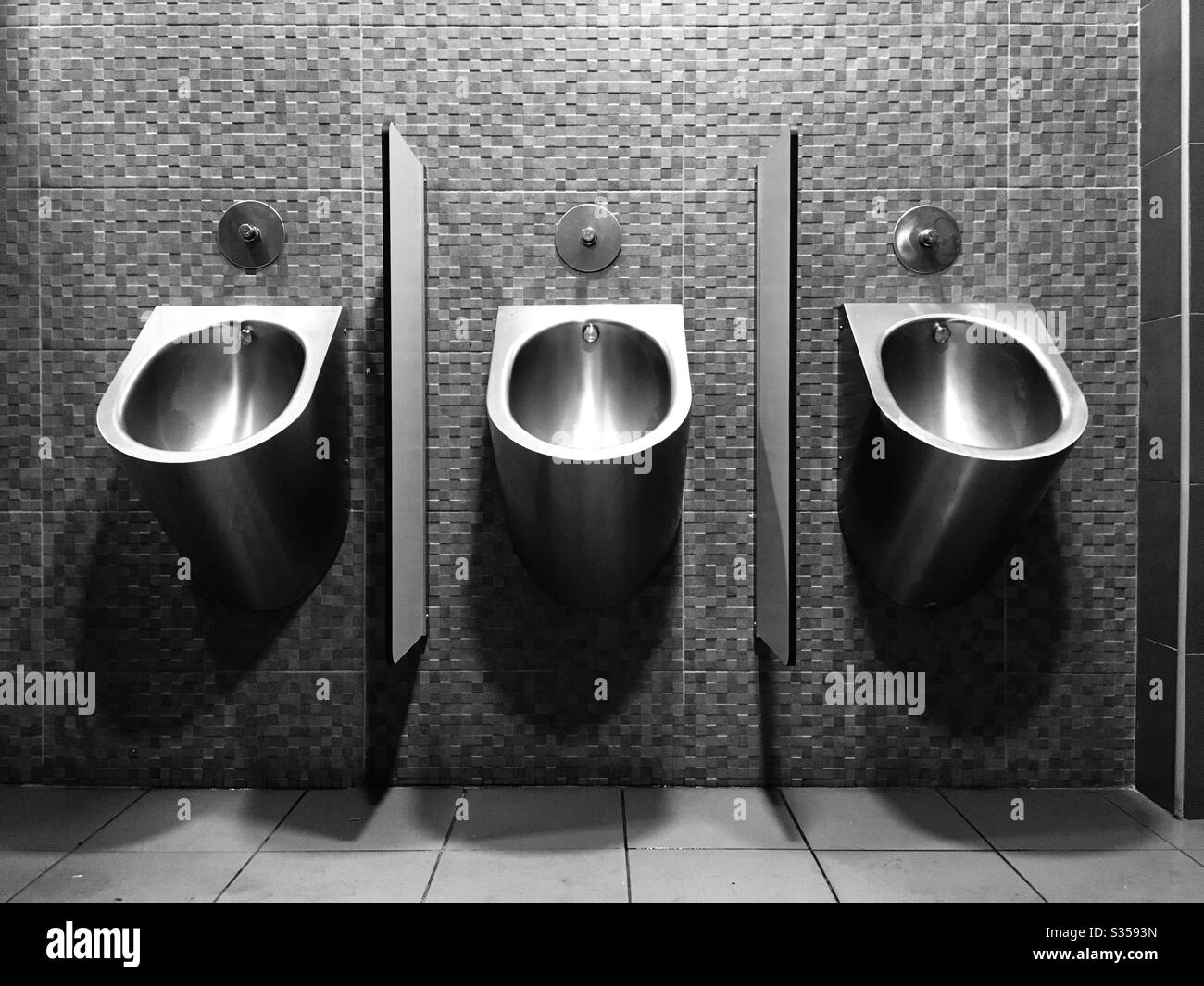 Urinals in muro di mattonelle. Foto in bianco e nero filtrate. Foto orizzontale. Foto Stock