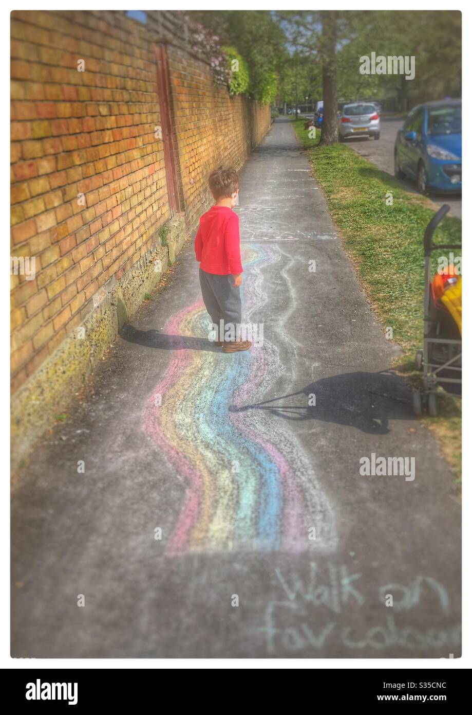Bambino bambino bambino piccolo bianco telaio camminare su pista arcobaleno gesso Foto Stock