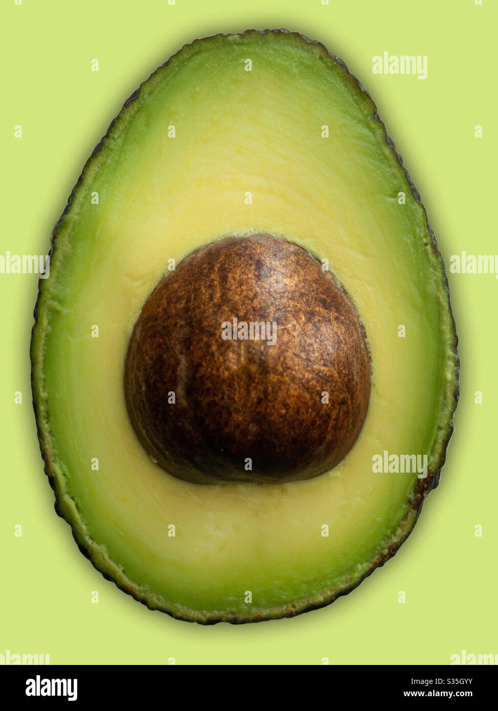 Metà isolata di avocado su sfondo giallo pallido. Cibo vegetariano sano per mangiare e per stare Foto Stock