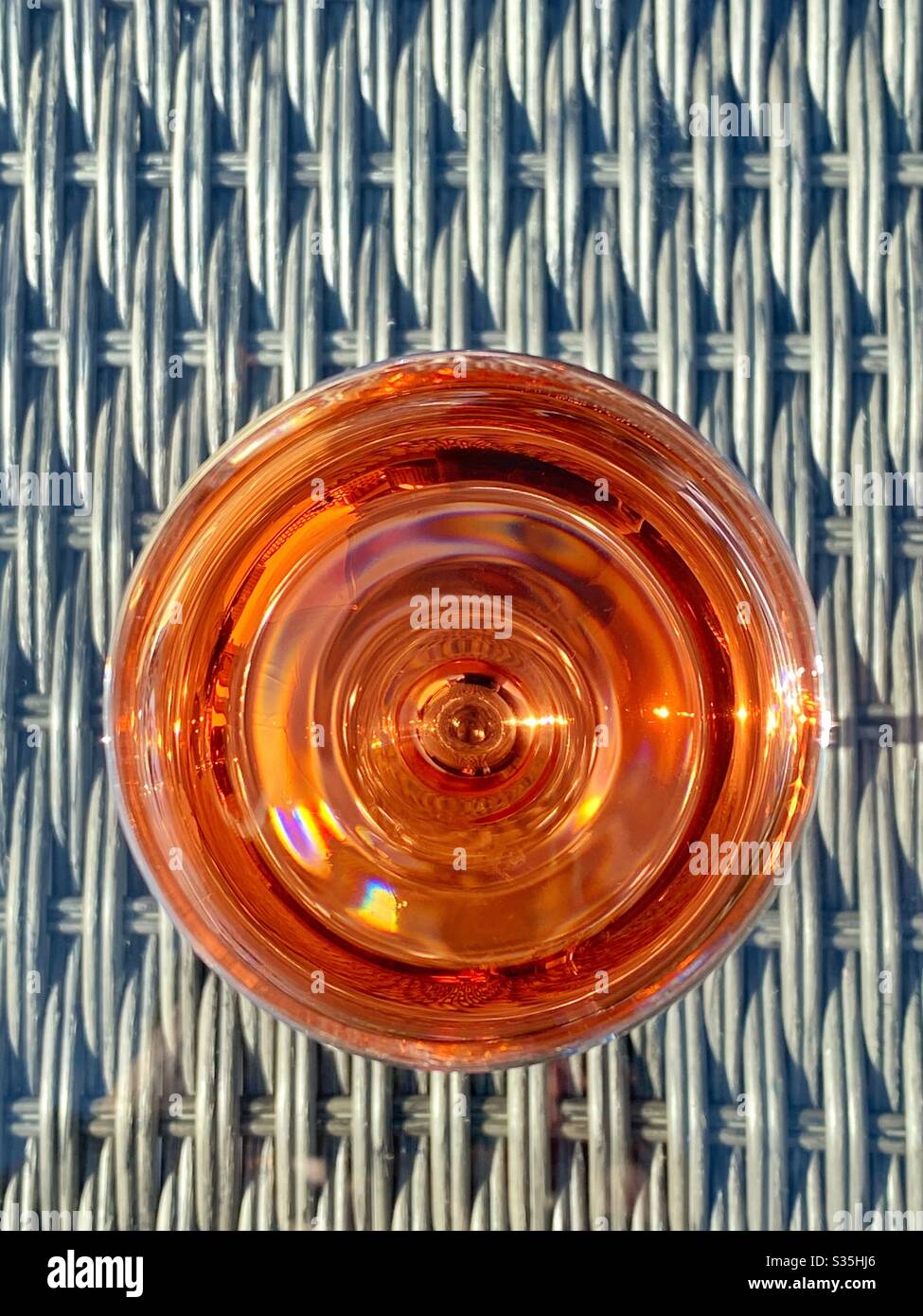 Bicchiere di vino rosato dall'alto sul piano di vetro dei mobili da giardino. Spazio per la copia. Foto Stock