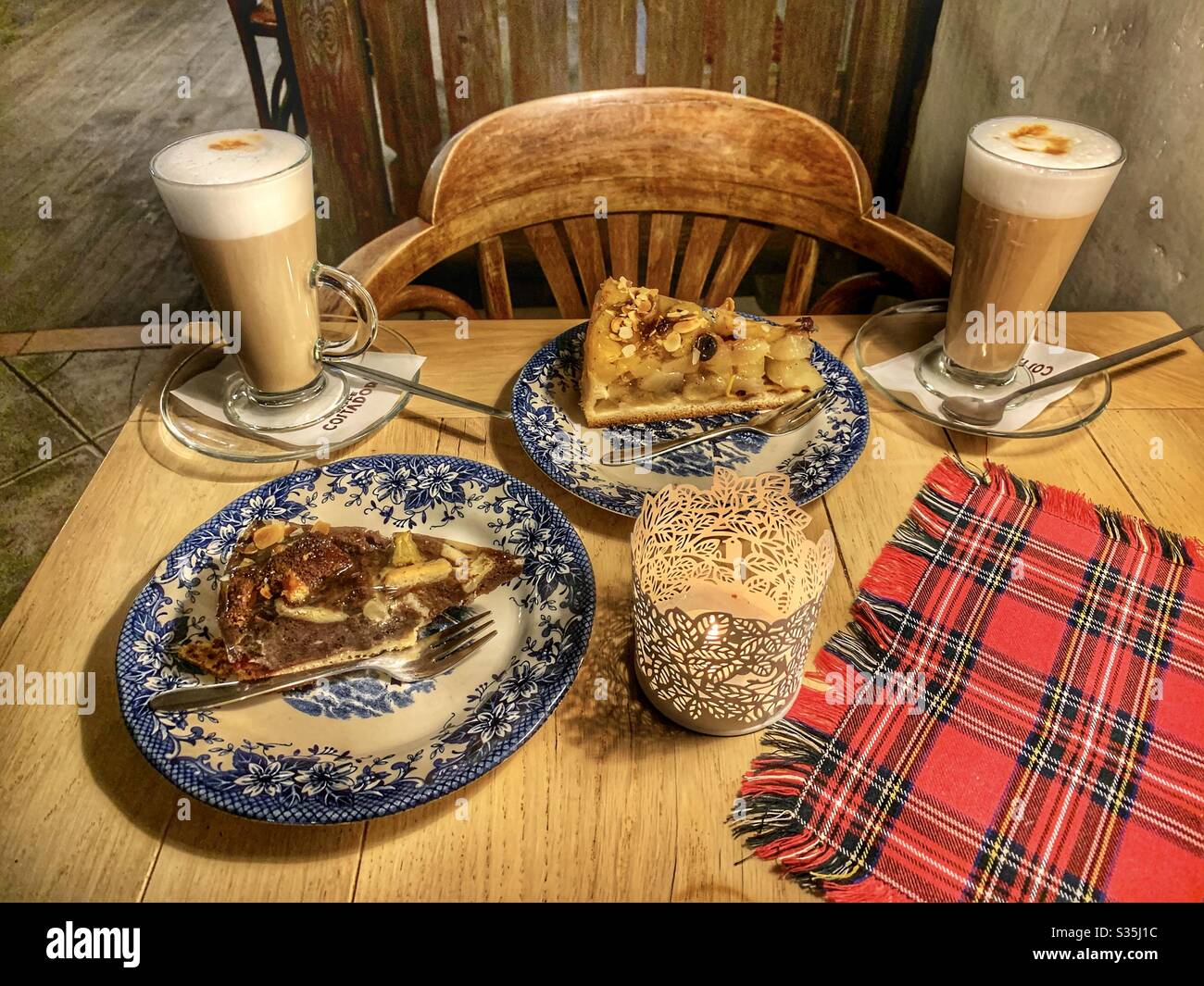 Caffè e torta su un rustico tavolo in legno con placemat tartan e candela. - Immagine stock catturata con smartphone