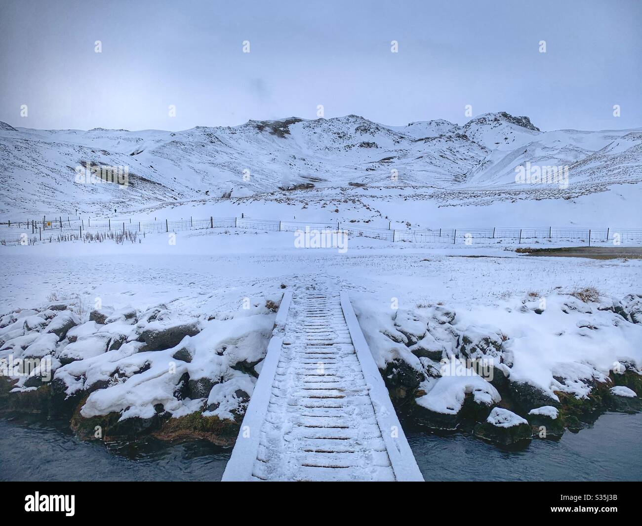 Passeggiata in snowboard su un fiume, che conduce ad un vasto paesaggio di montagna innevato. Monocromatico. Islanda. - Immagine stock catturata con smartphone