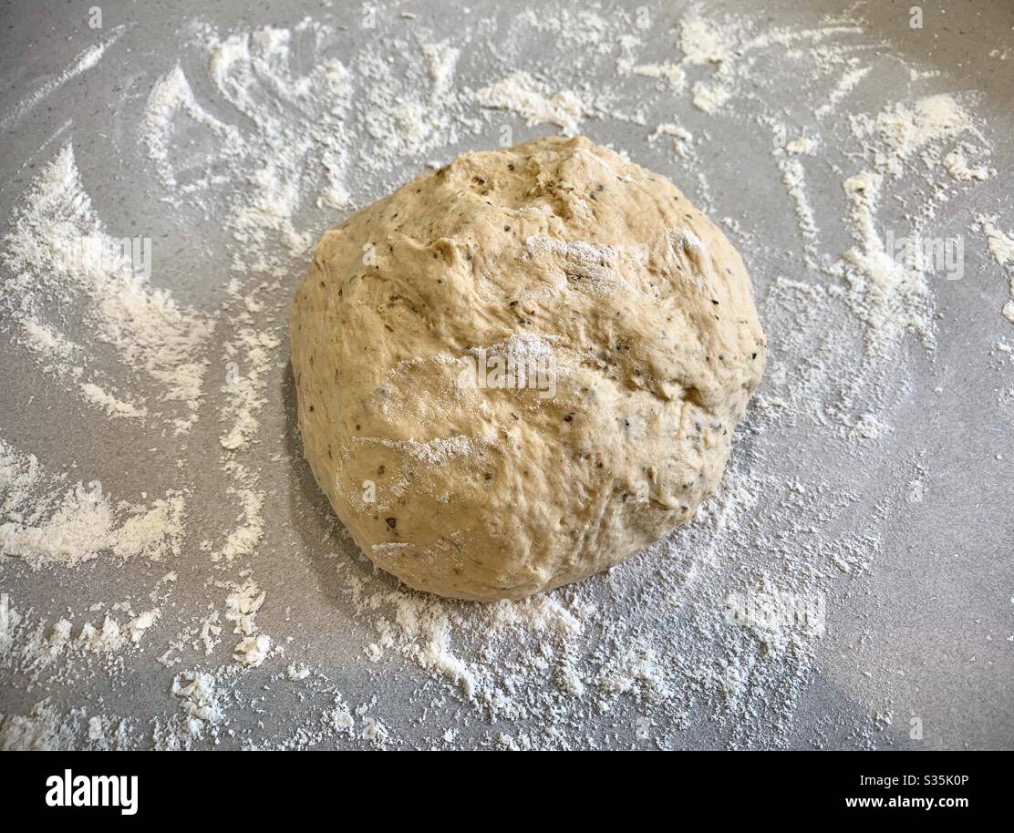 Fare il pane a casa. Una palla di pasta di pane è stata impastata su una superficie infarinata. - Immagine stock catturata con smartphone