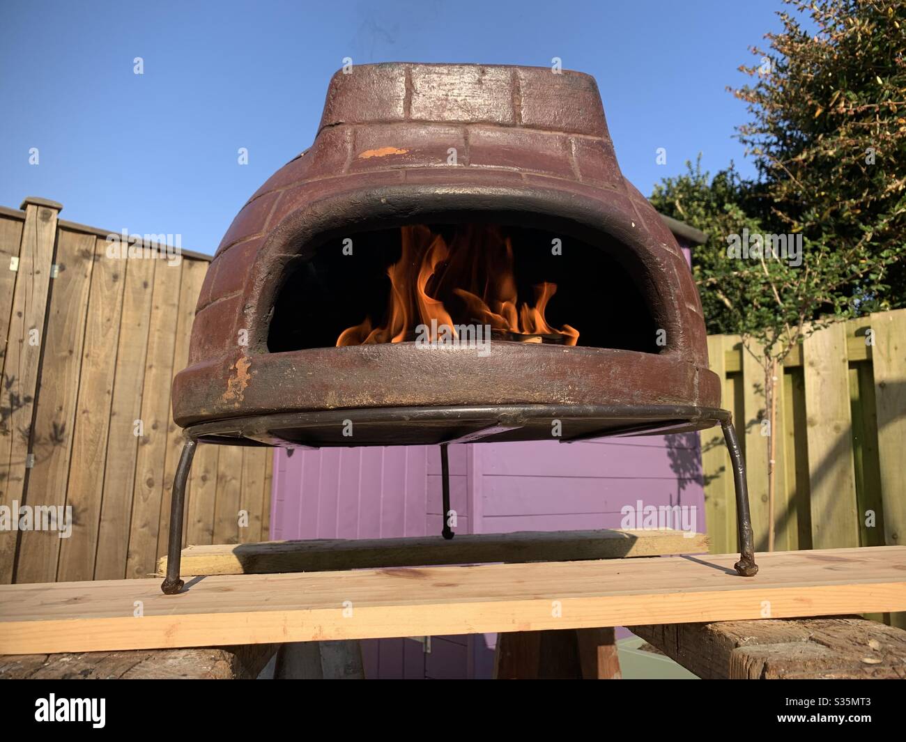 Fuoco all'interno di un mini forno per pizza in giardino. Foto Stock