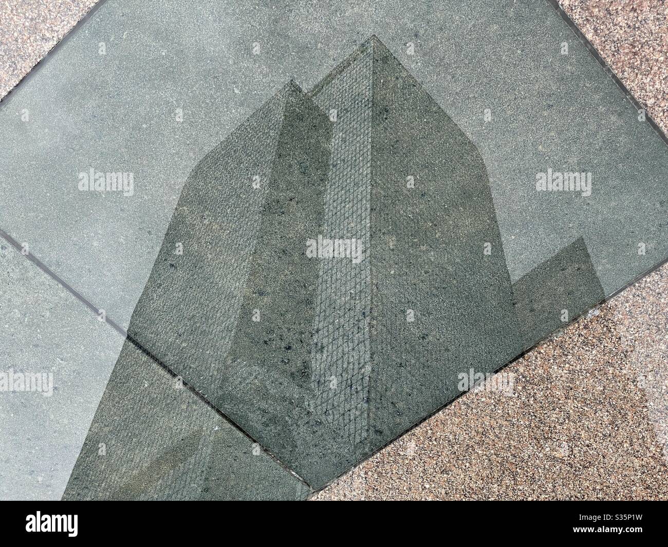 LOS ANGELES, CA, Apr 2020: Riflessione invertita dei grattacieli e delle nuvole in pozzanghera di pioggia sul marciapiede piastrellato, quartiere finanziario del centro Foto Stock