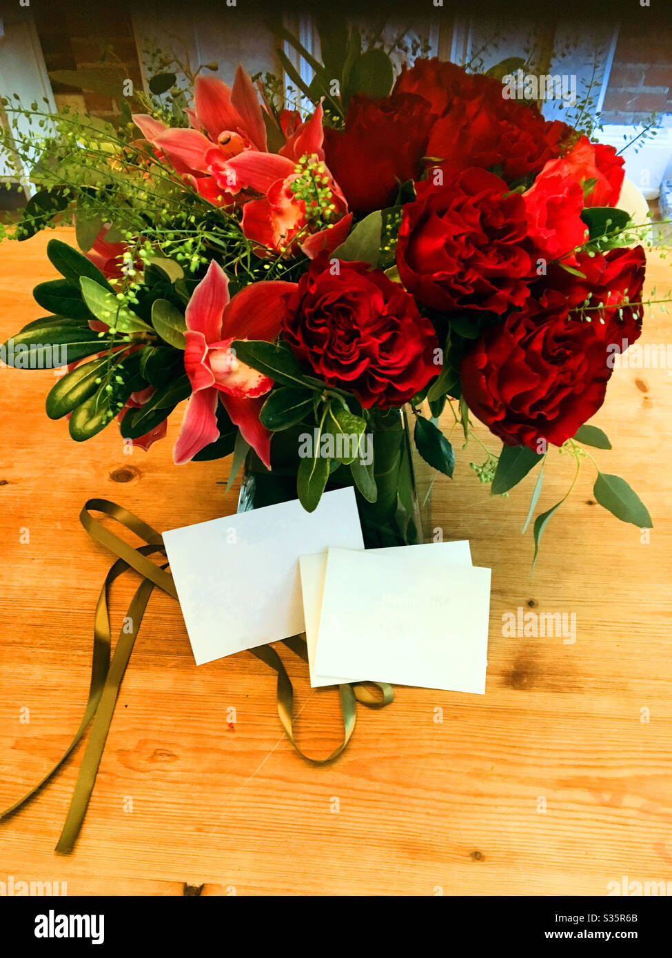 Ancora vita di un bel bouquet floreale di vari fiori rossi e schede di nota in bianco. - Immagine stock catturata con smartphone