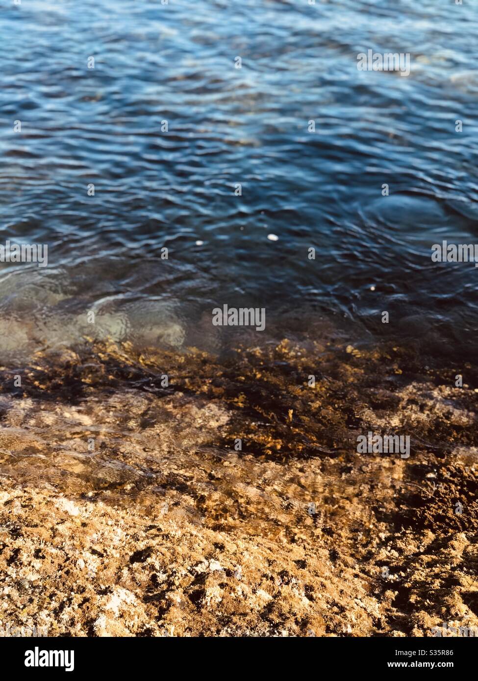 Un'immagine di filtro di tono caldo del bordo dell'oceano dove la costa rocciosa incontra l'oceano. Foto Stock
