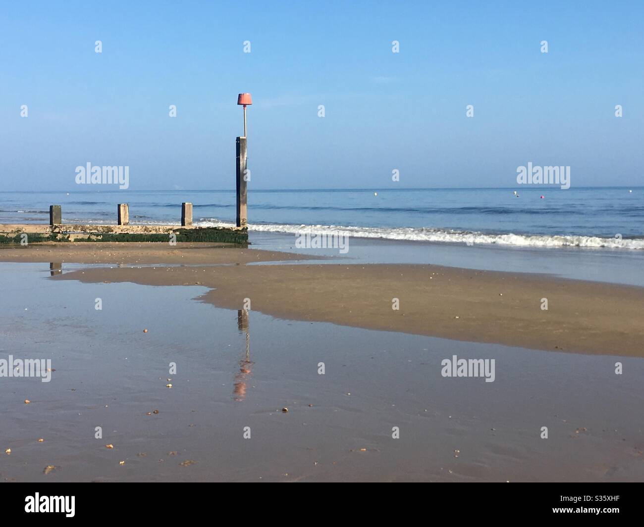 Riflessione di un Groyne a bassa marea su Boscombe Beach, Bournemouth, Dorset Foto Stock