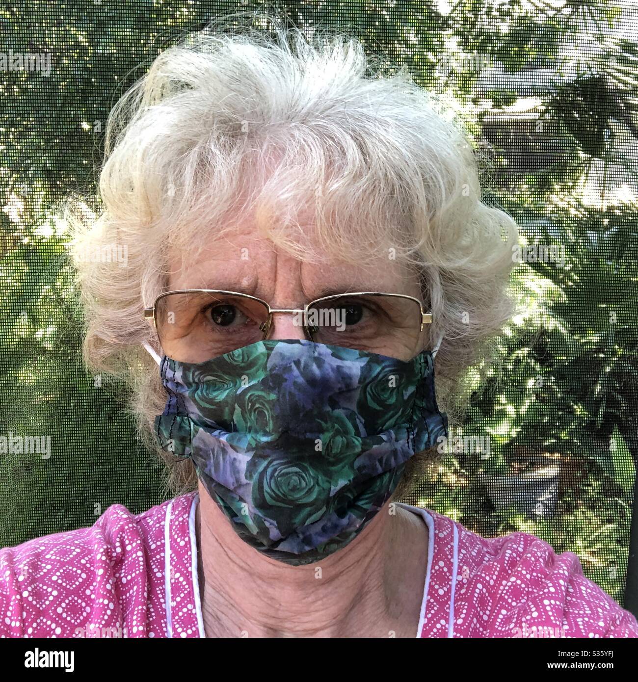 Selfie anziano con maschera facciale in tessuto fatta in casa. Foto Stock