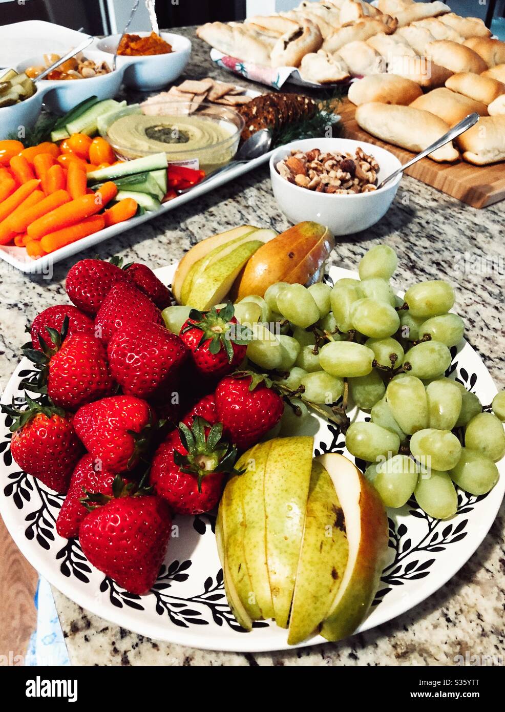 Piatto di salumi vegani con hummus, cetrioli, carote, pomodori, pepe, cracker e piatto di frutta e piroshi Foto Stock