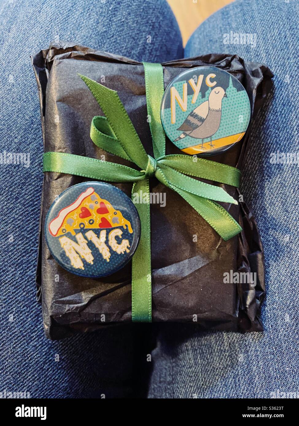 Piccolo regalo con bottoni NYC in braccio alla donna Foto Stock