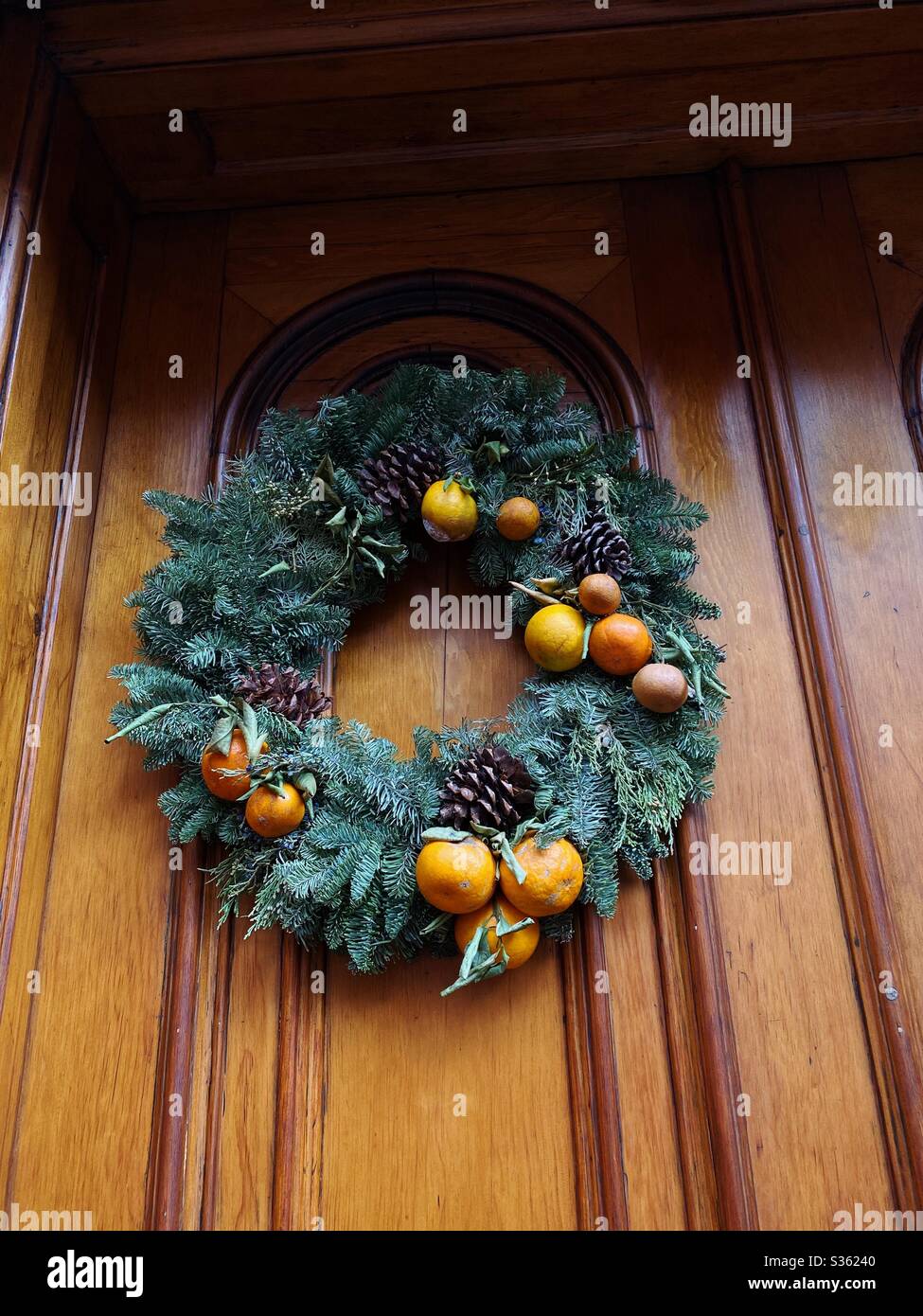 Corona di vacanza sulla porta con agrumi, arance e coni di pino Foto Stock