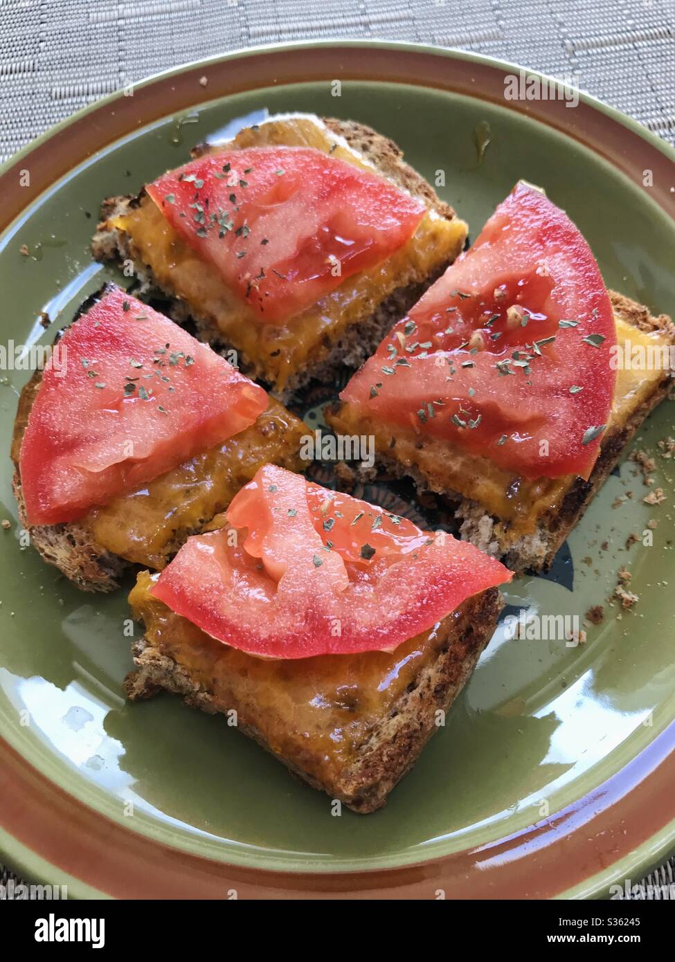 Tostare con formaggio fuso e pomodoro, tagliare a quattro pezzi su un piatto. Foto Stock