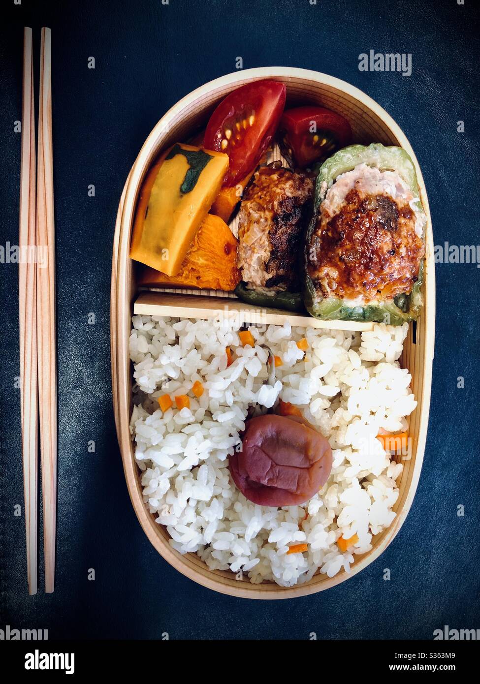 Pranzo fatto in casa con peperoni ripieni di carne tritati, zucca, pomodori, umeboshi e riso in una scatola di magewappa bento Foto Stock