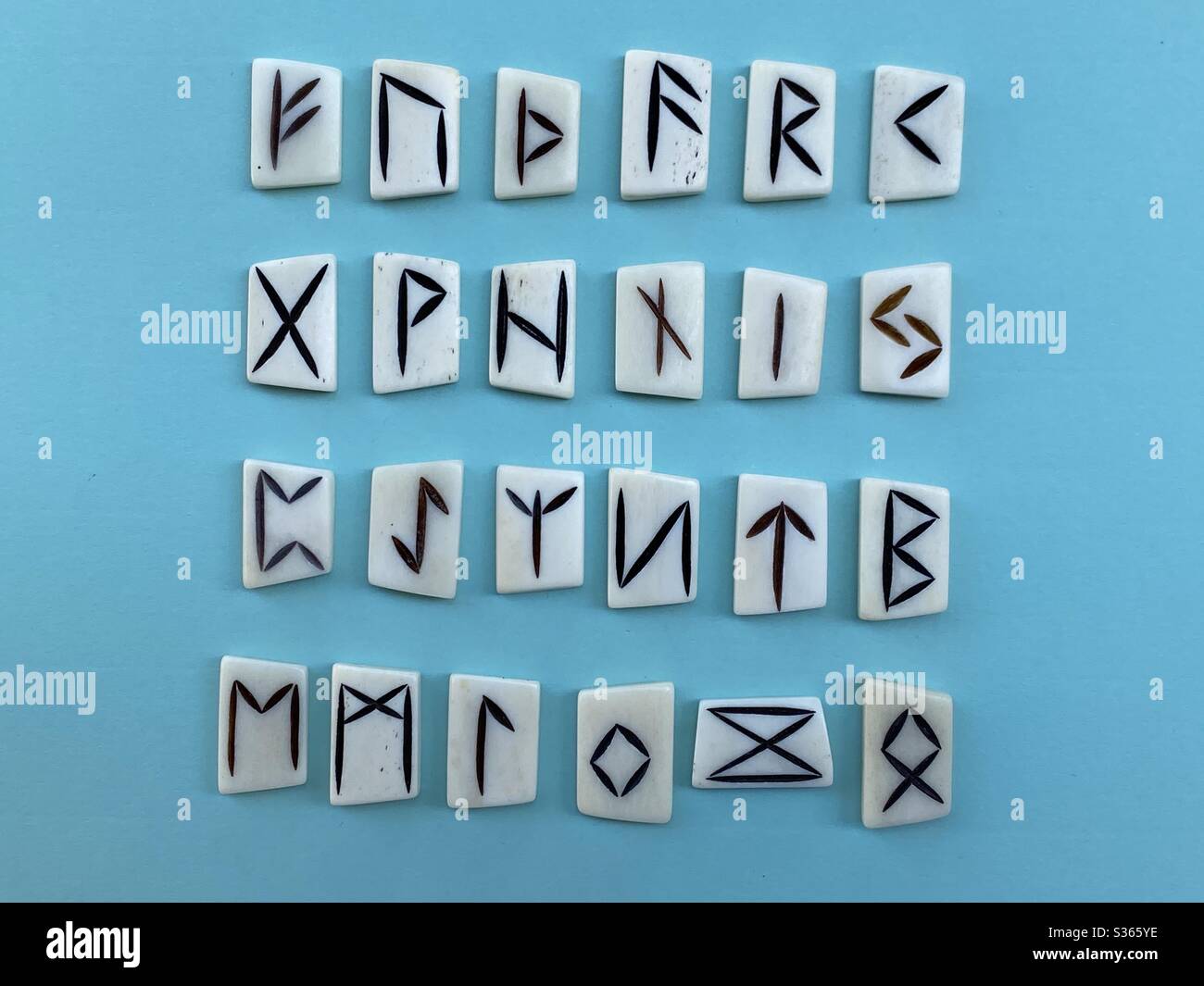 Alfabeto runico con pezzi d'osso intagliati su sfondo blu - Immagine stock catturata con smartphone