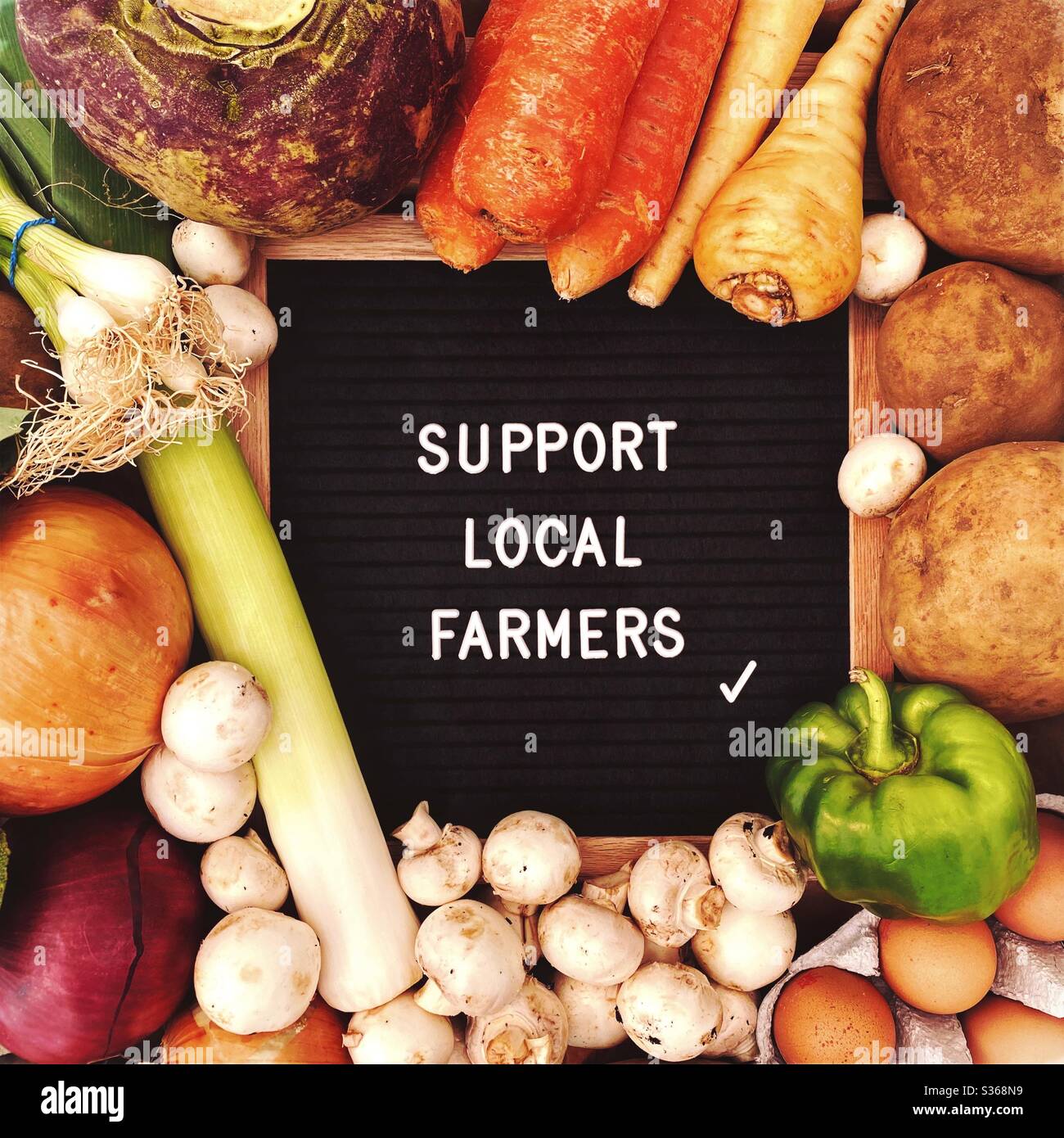 Sostenere gli agricoltori locali segno su uno sfondo rustico di verdure fresche, uova e prodotti. Agricoltura e agricoltura. Prodotti localmente, verdure biologiche e sane. - Immagine stock catturata con smartphone