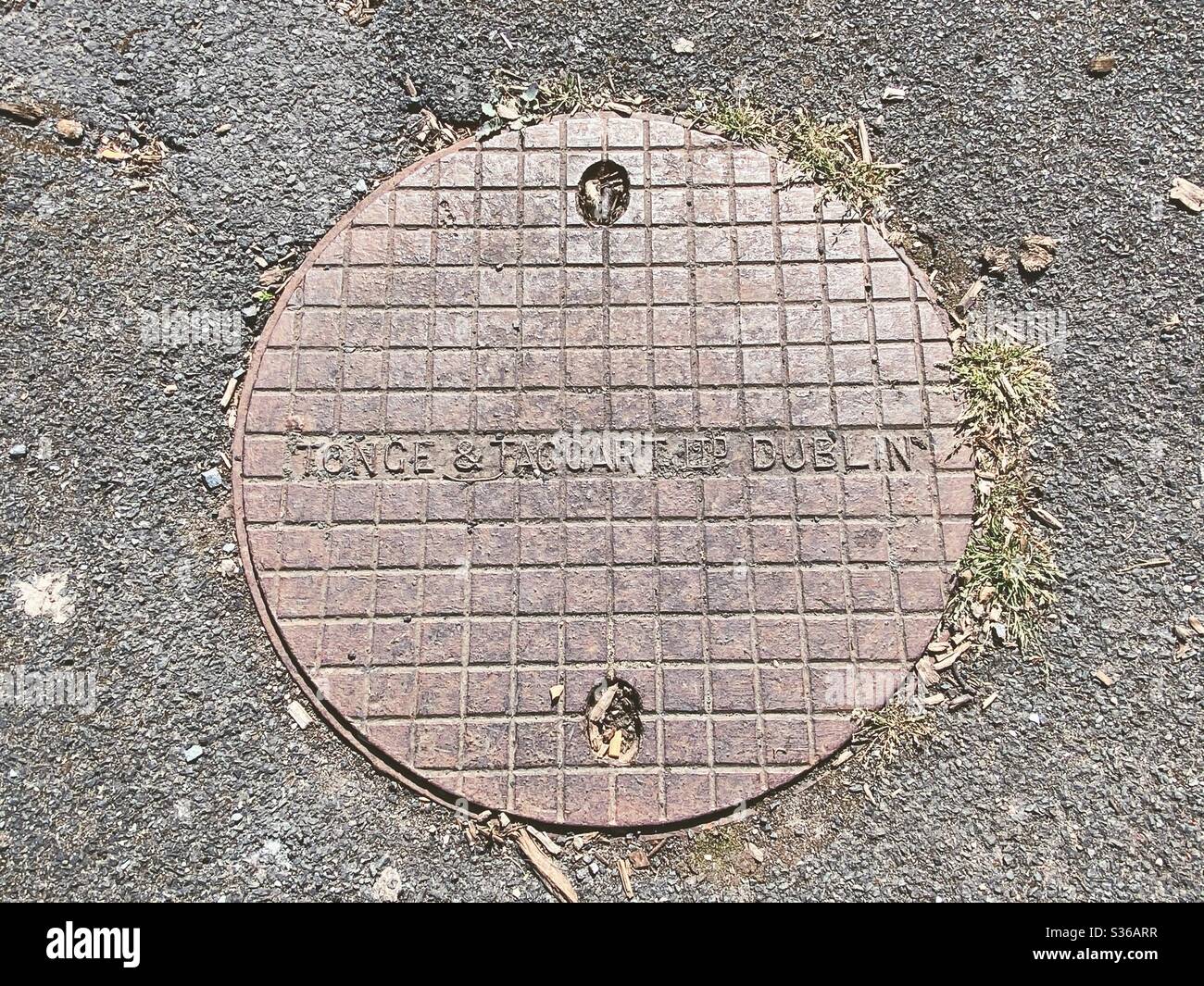 Una copertura per tombini prodotta da Tonge e Taggart di Dublino, Irlanda. Fondata nel 1869, la società ha continuato a operare fino al 1986. Foto Stock