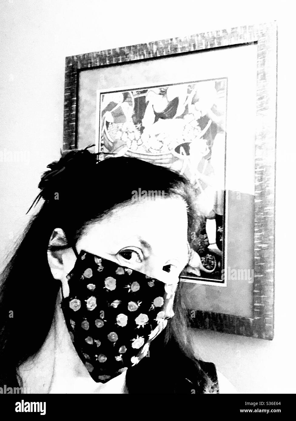 Ritratto monocromatico ad alto contrasto di una donna che indossa una maschera non chirurgica con un aspetto quizzical. Foto Stock